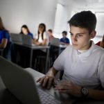 Male student using laptop on a computer class.