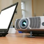 Laptop with computer projector on table